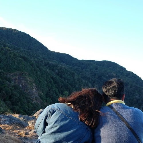 Namorados de costas vendo montanhas.